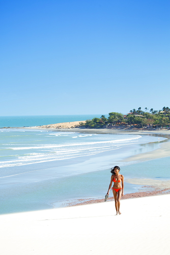 A young woman walking along the beach in Jericoacoara, Ceara, Brazil, South America