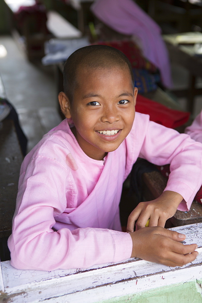 Buddhist novice schoolgirl sitting at her desk in the school classroom, Sagaing, Myanmar, Southeast Asia