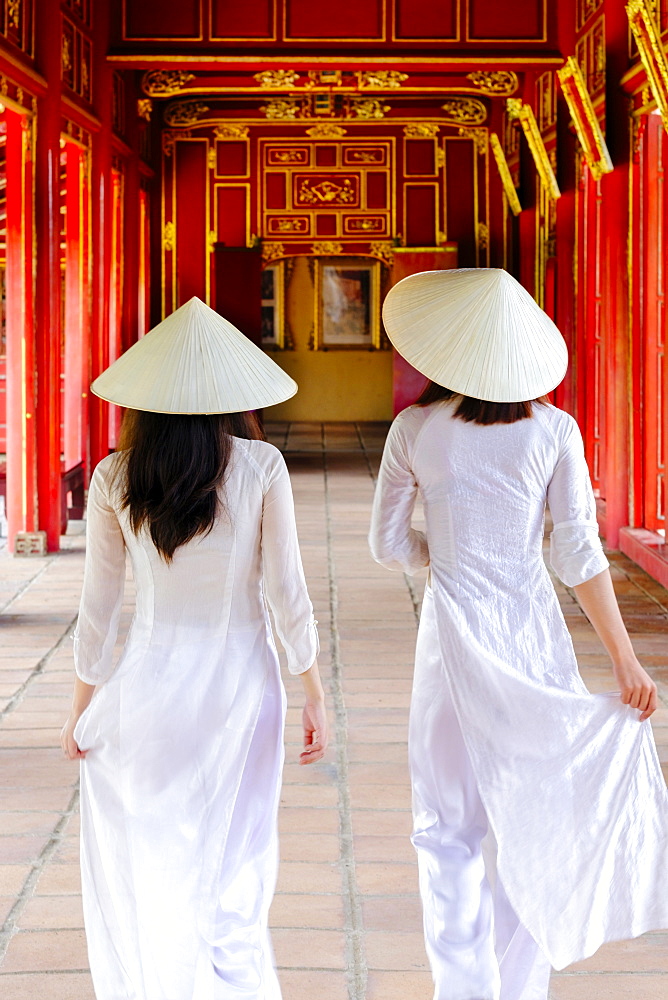 Two Vietnamese women in traditional Ao Dai dresses and Non La conical hats in the Forbidden Purple City of Hue, Thua Thien Hue, Vietnam, Indochina, Southeast Asia, Asia