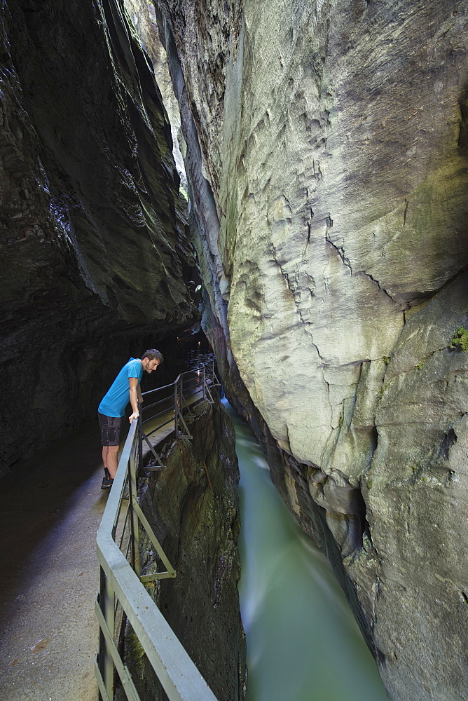 Hiker on walkway admires the creek in the narrow limestone gorge, Aare Gorge, Bernese Oberland, Canton of Berne, Switzerland, Europe