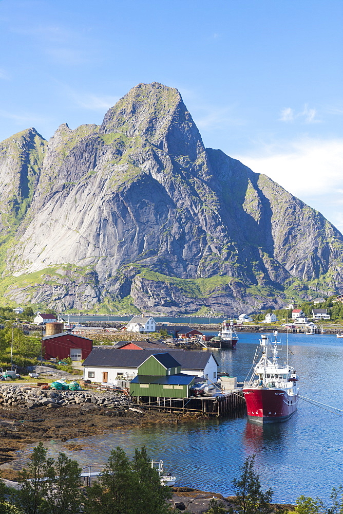 Ship in the blue sea frames the fishing village and the rocky peaks, Reine, Moskenesoya, Lofoten Islands, Norway, Scandinavia, Europe