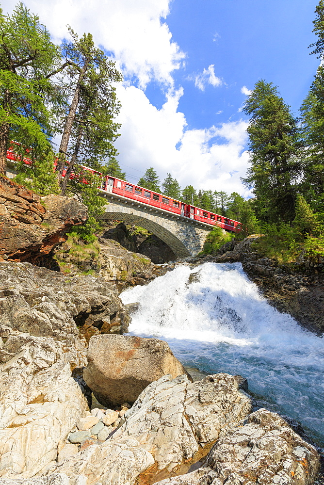 Bernina Express train above an alpine creek, Morteratsch, Engadine, Canton of Graubunden, Switzerland, Europe