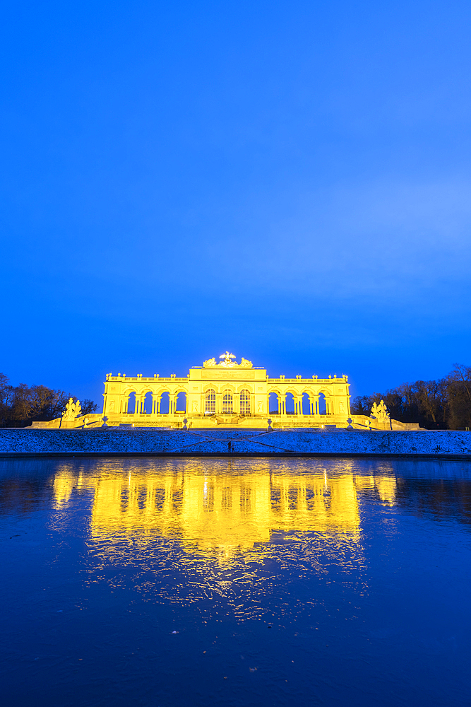 Illuminated Gloriette building mirrored in water at dusk, Schonbrunn Palace, UNESCO World Heritage Site, Vienna, Austria, Europe