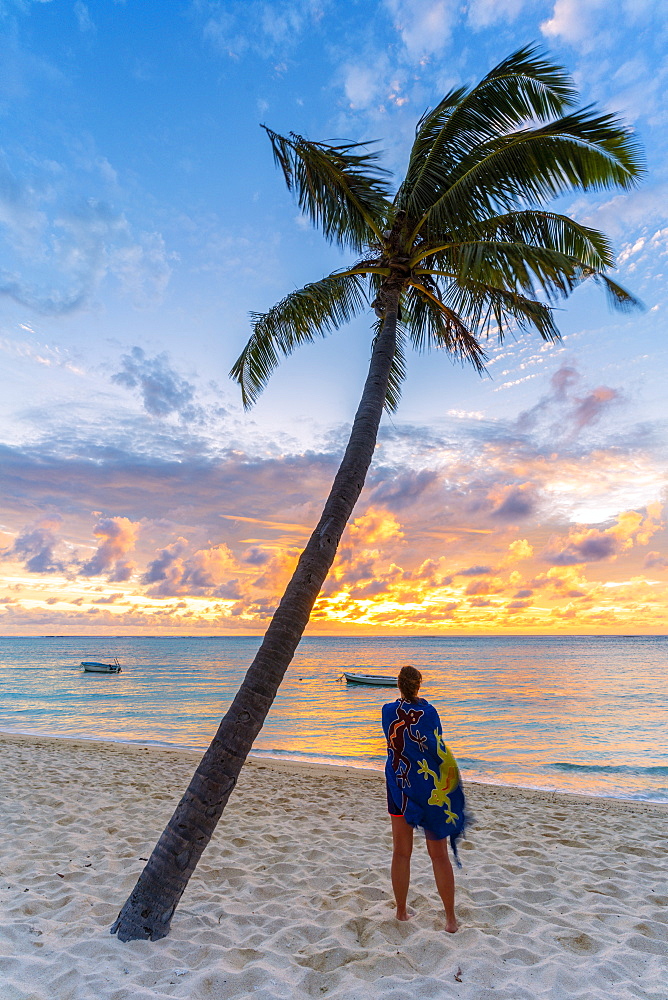 Rear view of woman with sarong admiring the ocean at sunset on palm-fringed beach, Le Morne Brabant, Black River, Mauritius, Indian Ocean, Africa