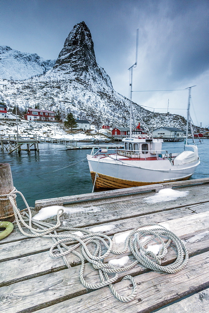 A boat moored in the cold sea in the background the snowy peaks, Reine. Lofoten Islands, Northern Norway, Scandinavia, Arctic, Europe