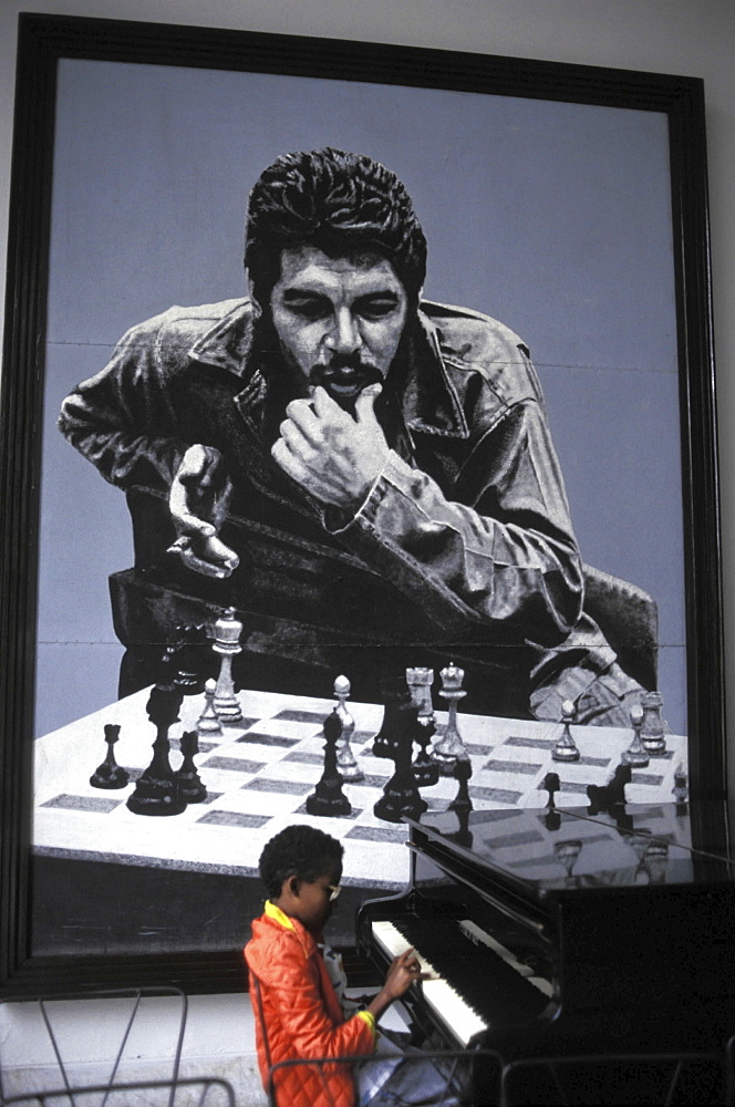 Che' guevara, cuba. A boy playing the piano in front of an iconic picture of the argentinian guerilla leader