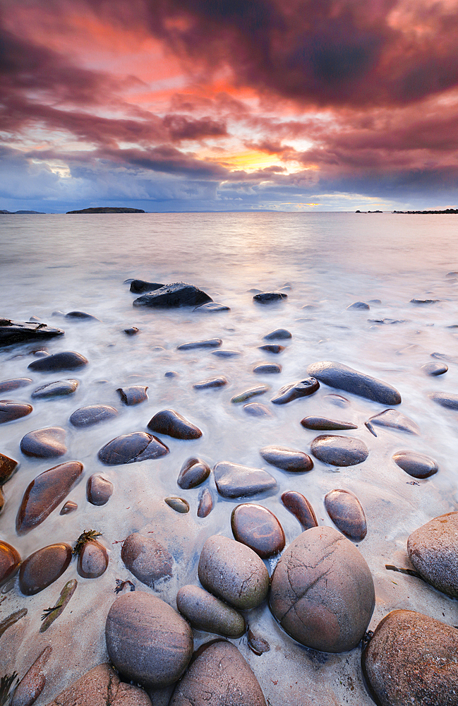 Rocks and sandy beach at Reiff Bay with the Summer Isles in the background during colourful sunset on the shores of northwest Scotland, Highland, Scotland, United Kingdom, Europe