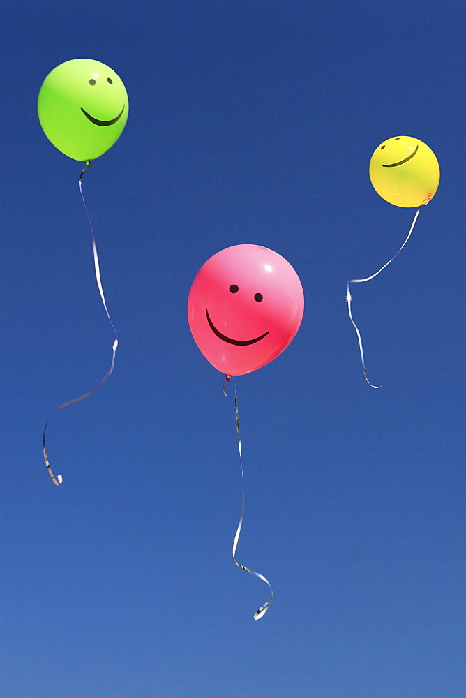 Coloured smily balloon in blue sky, switzerland