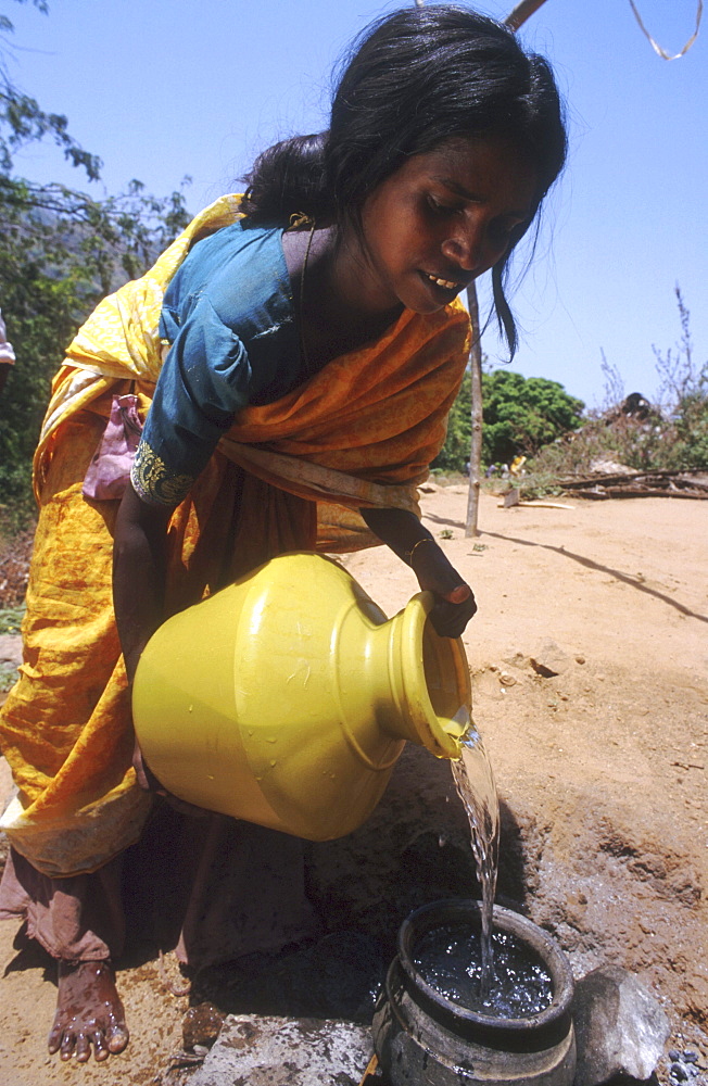 India - water: woman filling cooking pot with water, tamil nadu