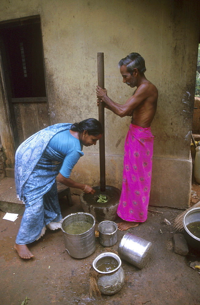 India - food: man and woman grinding herbs, pinkulam village, kerala