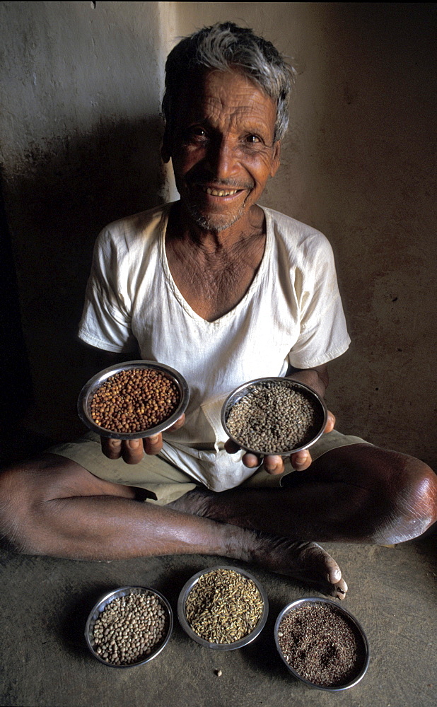 India farmer muniyappa, displaying traditional lentil seeds, horse, red, cow and finger millet. Alaganahalli village, kolar, karnataka