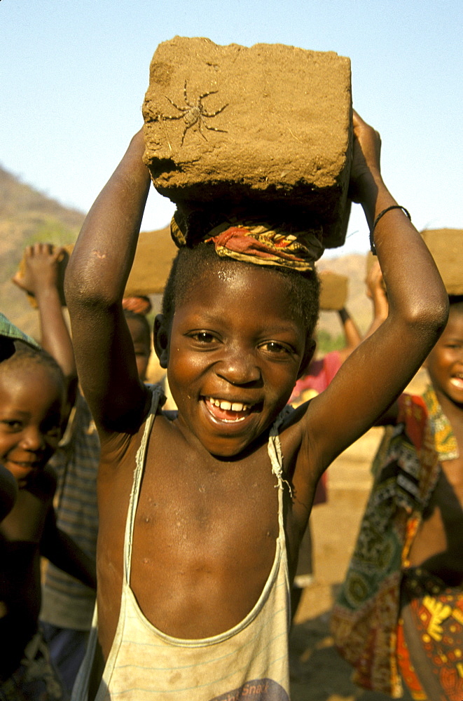 Mozambique boy carrying mud brick, school building project, metangula