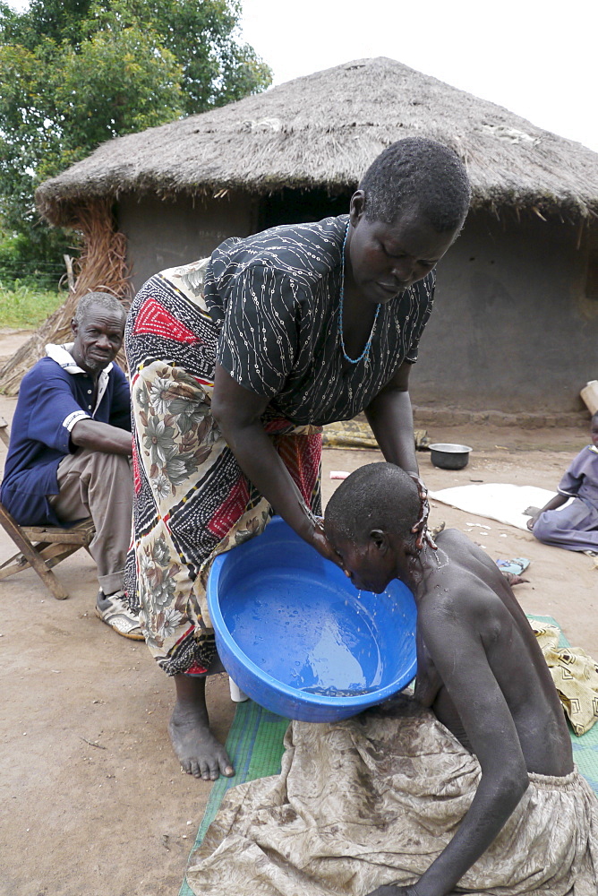 UGANDA The work of Comboni Samaritans, Gulu. Visiting Atoo Alice, 48, who has AIDS and suffers from depression. She lives with her 52-year-old sister Ventorina Ayo who is her primary care giver, and with her husband Michael. Michael and Ventorina are very loving and slo look after Alice's two children, Geoffrey and Enice, both of whom are epileptic. They have taken on a huge committment, and are helped by the Combonis who bring supplioes and food. Ventorina washing and dressing Alice. PHOTO by Sean Sprague