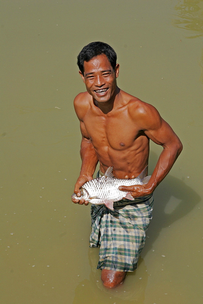 Bangladesh farid pathang with a fish caught in his pond, garo tribal minority haluaghat, mymensingh region