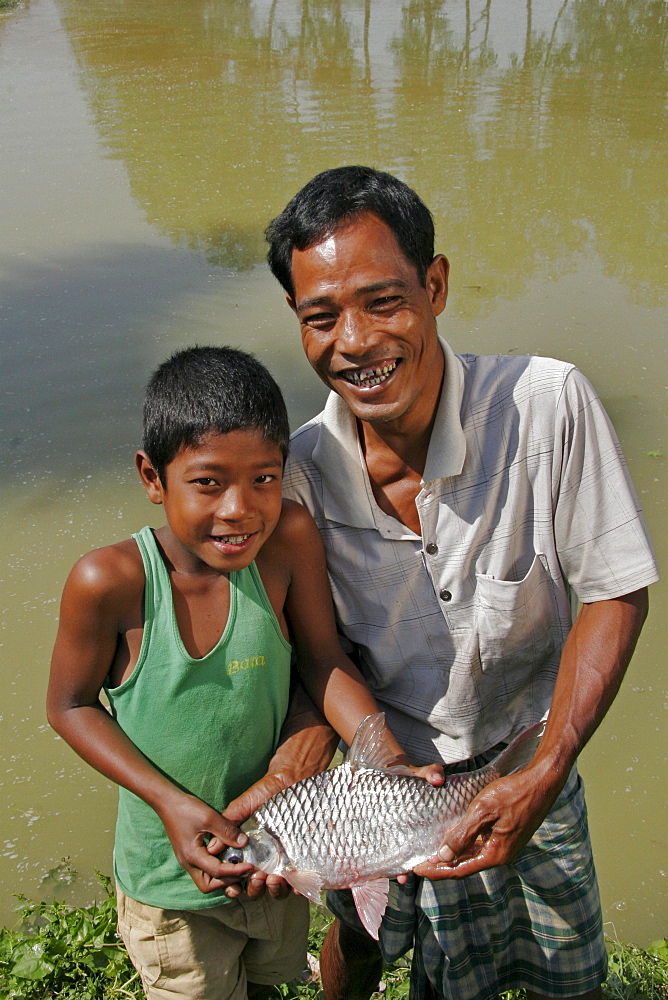 Bangladesh farid pathang and son homar with a big fish caught in their pond garo tribal minority haluaghat, mymensingh region