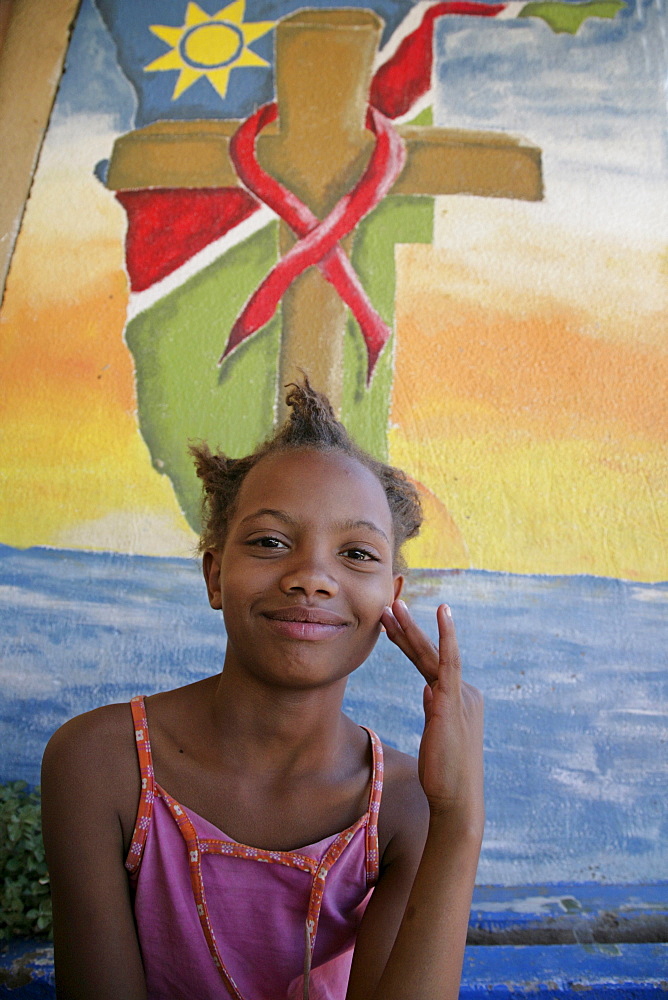 Namibia child at bernard nordkamp (youth) center, katatura, a black township of windhoek, dating from apartheid. country very high rates, mural behind depicts struggle against aids