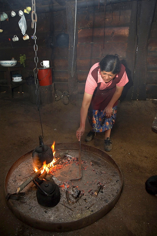 Chile. Mapuche woman heating water in her kitchen, temuco