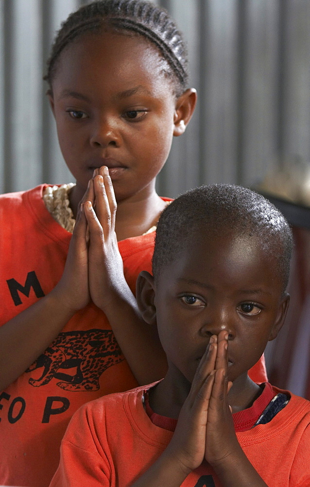 Kenya. Faces of the congregation at catholic mass in mukuru ruben, a slum of nairobi. Children praying