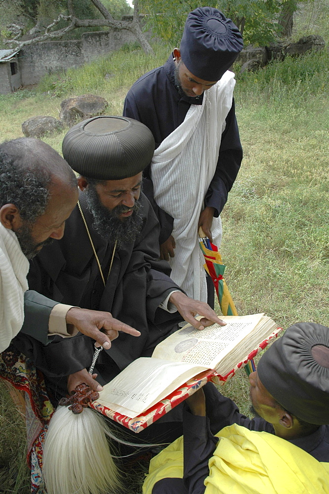 Religion, ethiopia. Orthodox archbishop gregorius visiting tullo gudo island and monastery of debre zion, lake ziway. Reading ancient parchment bibles and manuscripts stored in church.