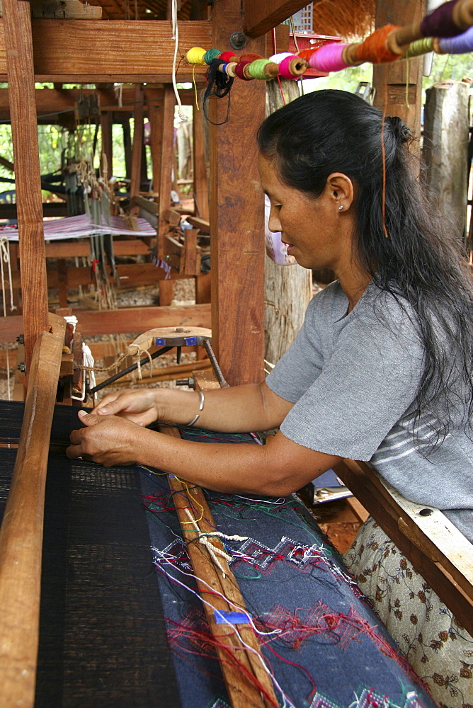 Thailand woman using a large loom for weaving cotton cloth, chiang dao village, near chiang mai