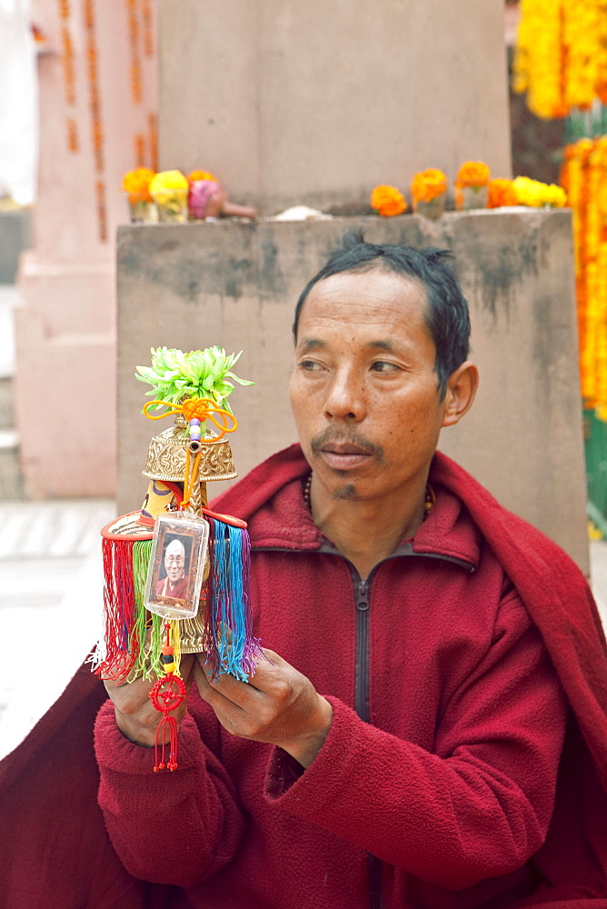 Buddhist monk holding blessed water in a vessel with hh dalai lama amulet. Inside mahabodhi temple. Kalachakra initiation in bodhgaya, india  