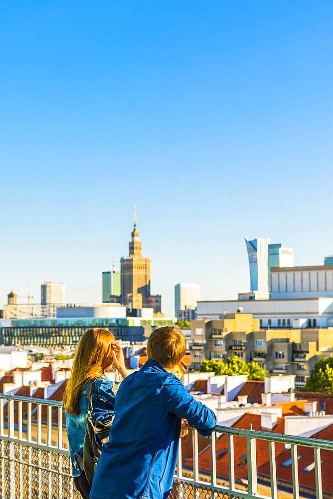 Couple looking at Palace of Culture and Science and skyscrapers, City Centre, Warsaw, Poland, Europe