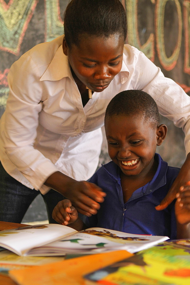 Isingizwe Alice, 8 years old, who is dumb and her teacher Musabyemariya Alphonsine from Ngwino Nawe, teaching Alice how to read a book using signs, Rwanda, Africa