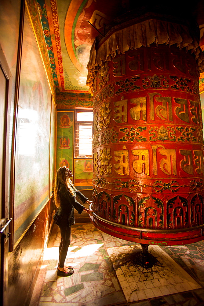 Woman praying at a Buddhist prayer wheel in Bouddha (Boudhanath) temple, UNESCO World Heritage Site, Kathmandu, Nepal, Asia