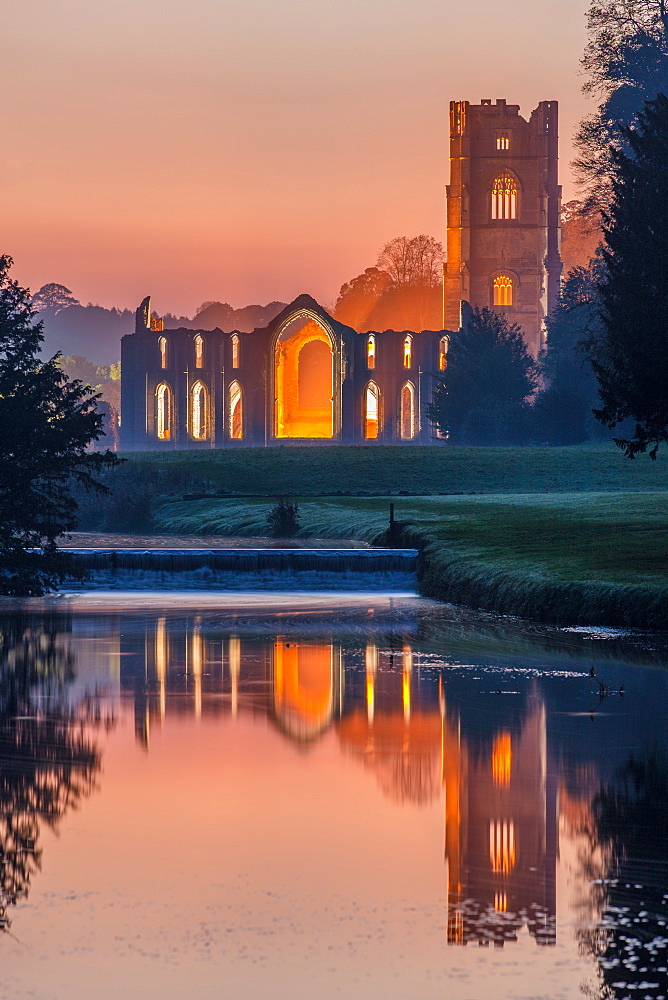 The Cistercian monastery of Fountains Abbey lit at dusk and reflected in the River Skell, UNESCO World Heritage Site, North Yorkshire, Yorkshire, England, United Kingdom, Europe