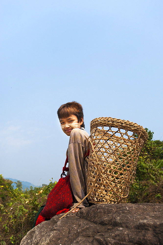 A boy with a doko (back basket) wearing powdered sandalwood on his face for decoration, Kachin State, Myanmar (Burma), Asia