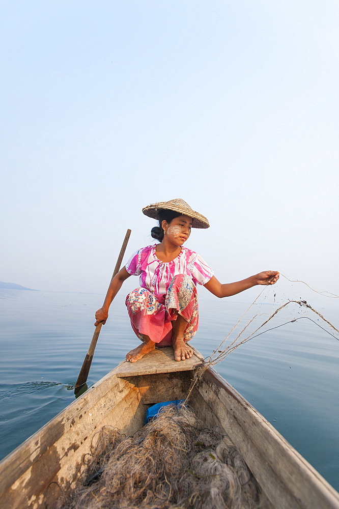 A young woman pulls in her nets at the end of the day on Indawgyi Lake, Kachin State, Myanmar (Burma), Asia