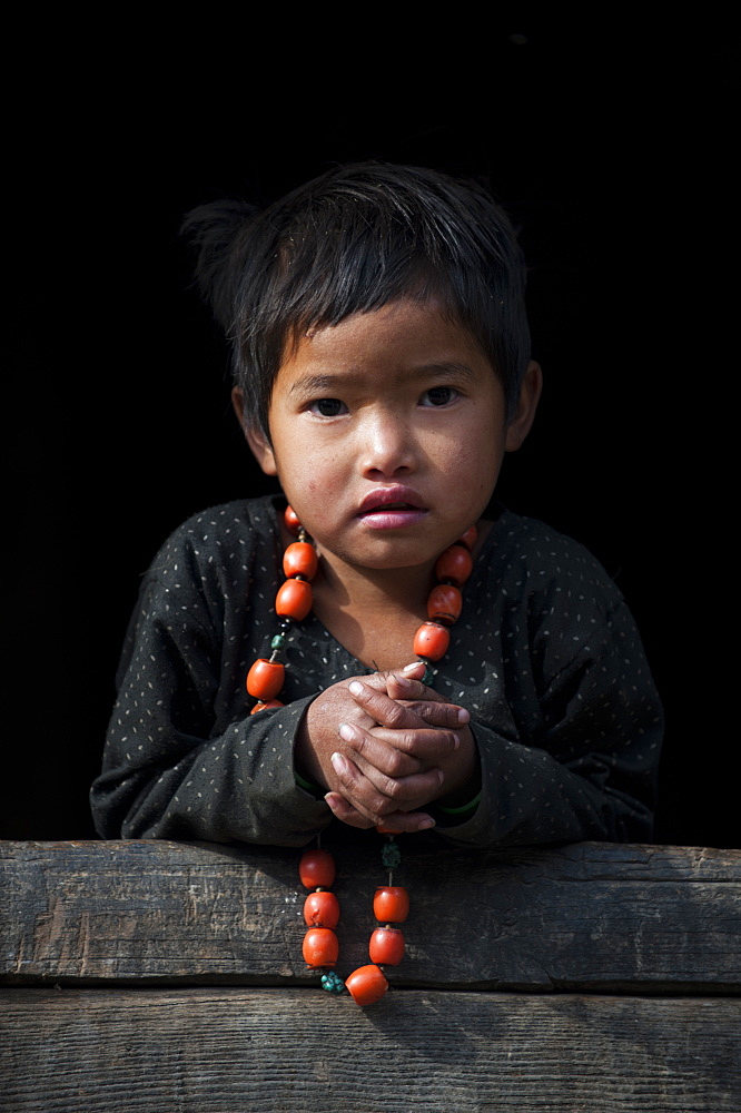 A little girl plays with her necklace in the Manaslu region of Nepal, Asia