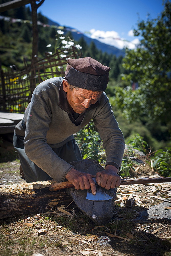 A Tamang man in the Tamang Heritage region close to Langtang sharpens an axe in the traditional way, Langtang Region, Himalayas, Nepal, Asia