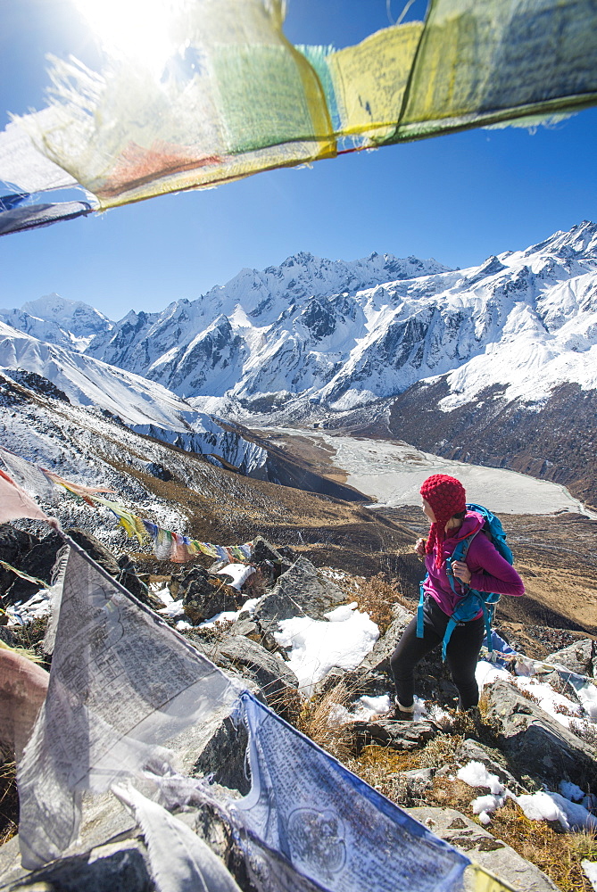 A woman trekking in the Langtang valley in Nepal stands on the top of Kyanjin Ri and looks out towards Ganchempo in the distance, Langtang Region, Nepal, Asia