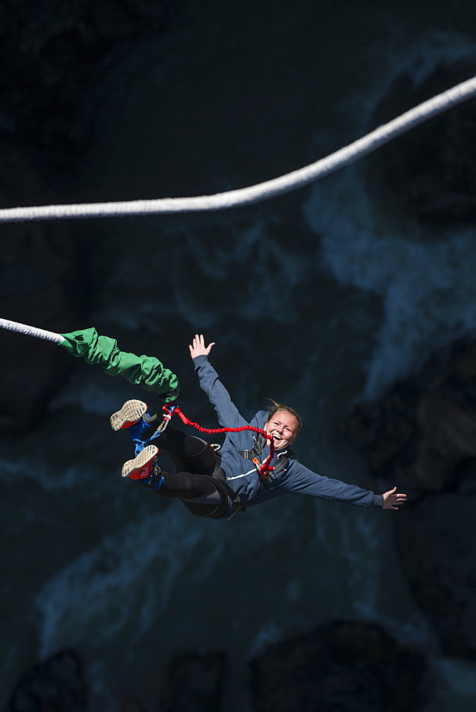 A woman smiles for the camera as she is bounced back up during a Bungee jump at The Last Resort, Nepal, Asia