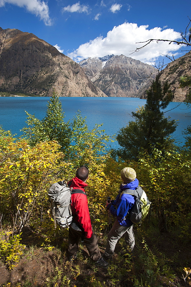 Trekkers look out at the turquoise blue Phoksundo lake, Dolpa Region, Nepal, Asia