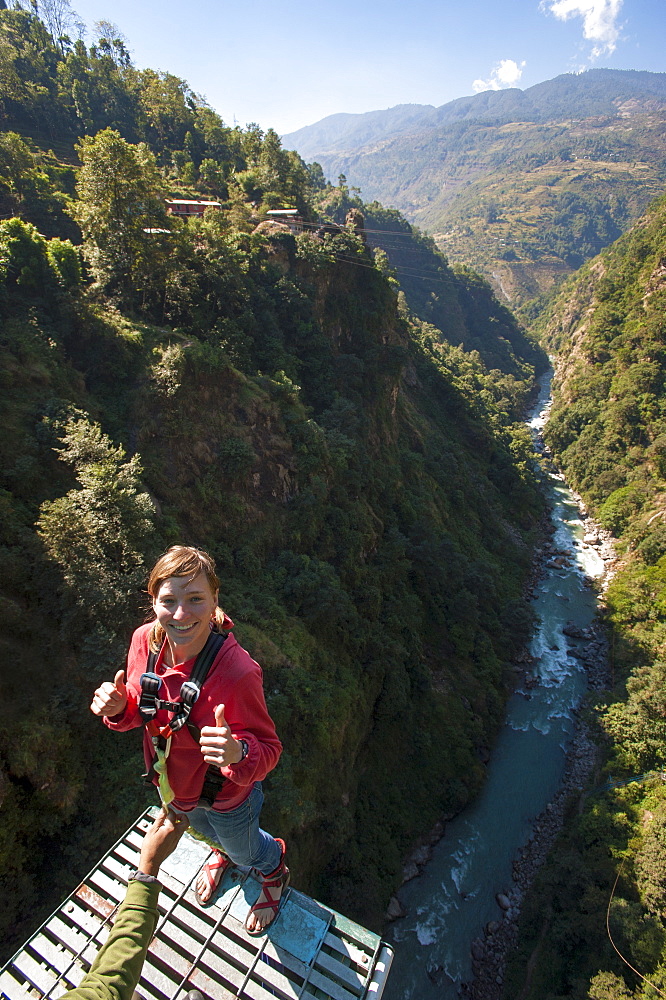 Standing on then edge, a girl prepares herself to take a bungy jump backwards, Nepal, Asia