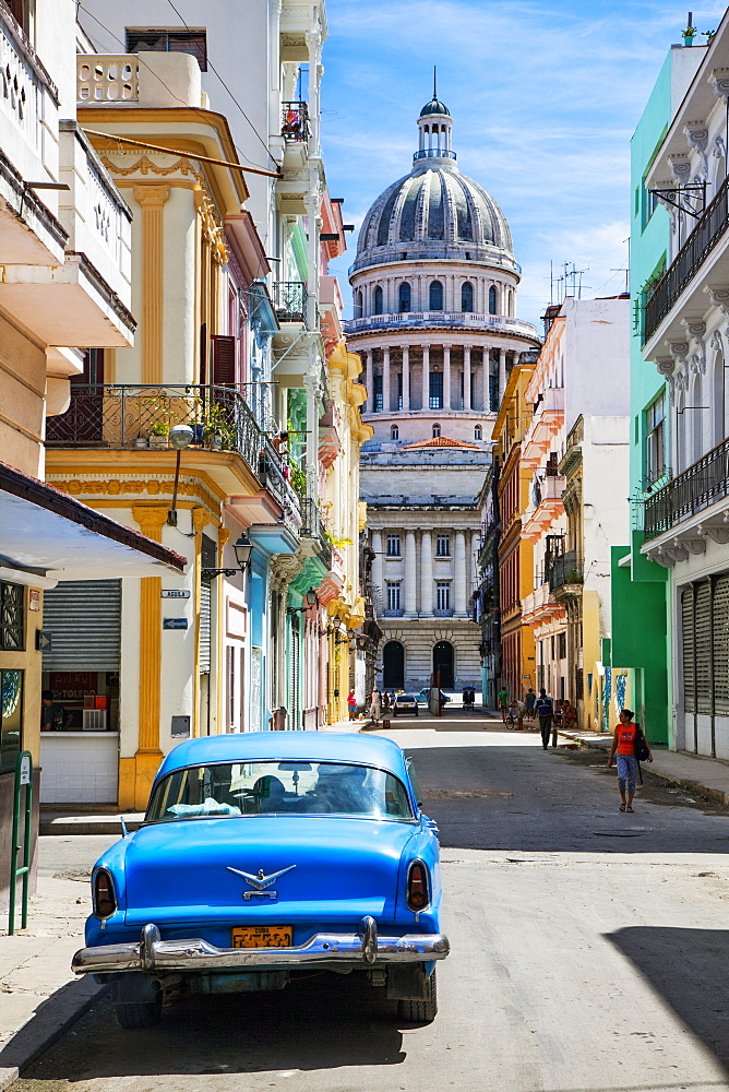 A classic car parked on the street next to colonial buildings with the former Parliament Building in the background, Havana, Cuba, West Indies, Caribbean, Central America