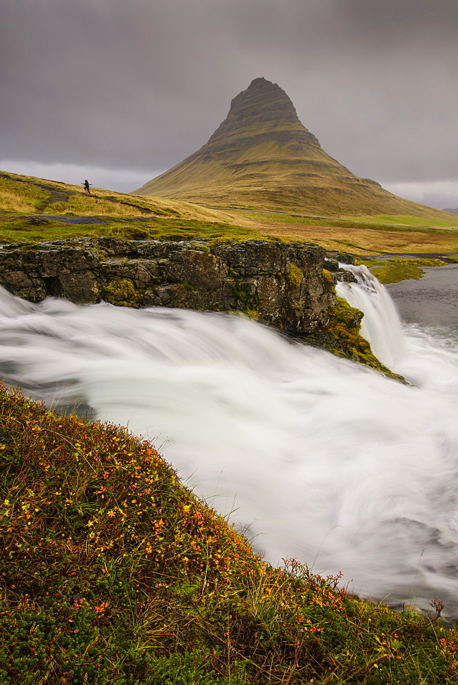 Kirkjufellsfoss in autumn with hiker to show scale, Iceland, Polar Regions