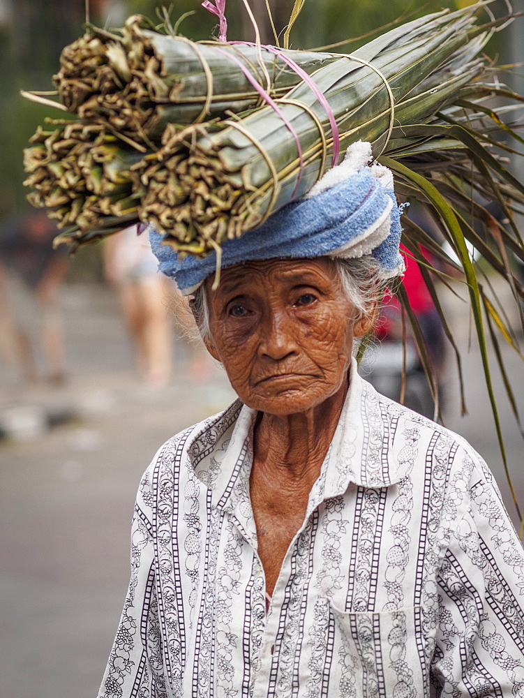 Old woman carries palm leaves on her head, Ubud, Bali, Indonesia, Southeast Asia, Asia