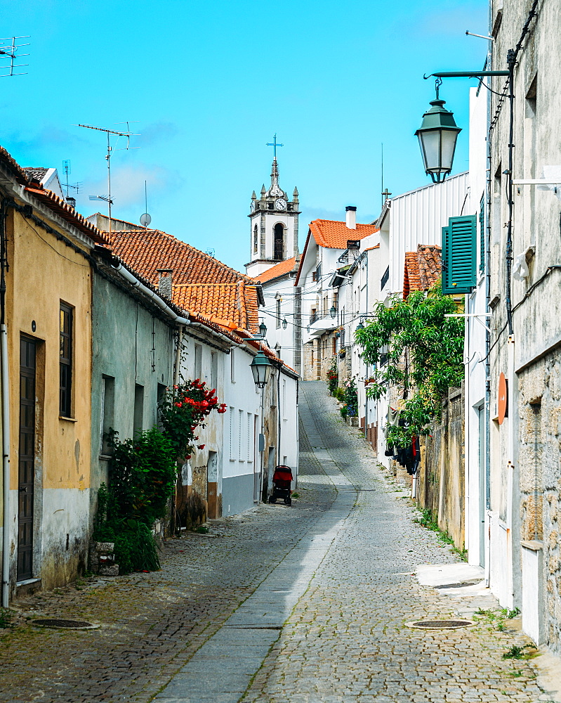 Narrow cobblestone street looking towards Santiago Church in Belmonte, Castelo Branco, Portugal, Europe