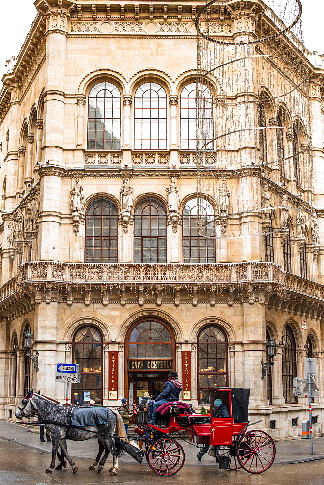 A traditional horse drawn carriage passes the historic Cafe Central cafe in Vienna, Austria, Europe