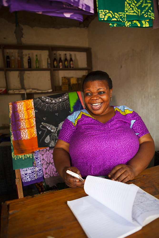 A woman smiling behind the counter of her shop, Tanzania, East Africa, Africa