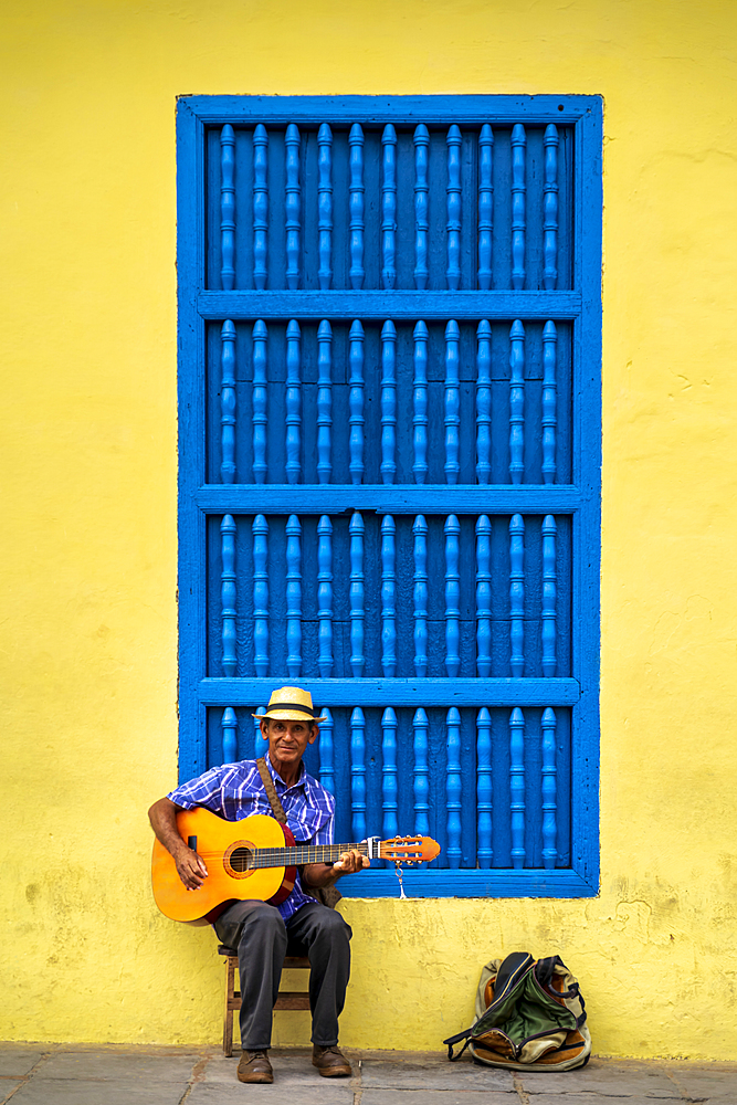 An elderly Cuban sitting on a chair playing a guitar, Trinidad, Sancti Spiritus Province, Cuba, West Indies, Caribbean, Central America