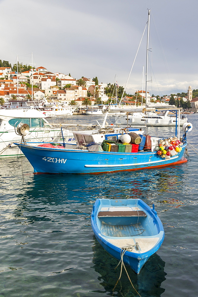 Colorful boat anchoring in the port of Hvar Town with view to the old town in the background, Hvar, Croatia, Europe