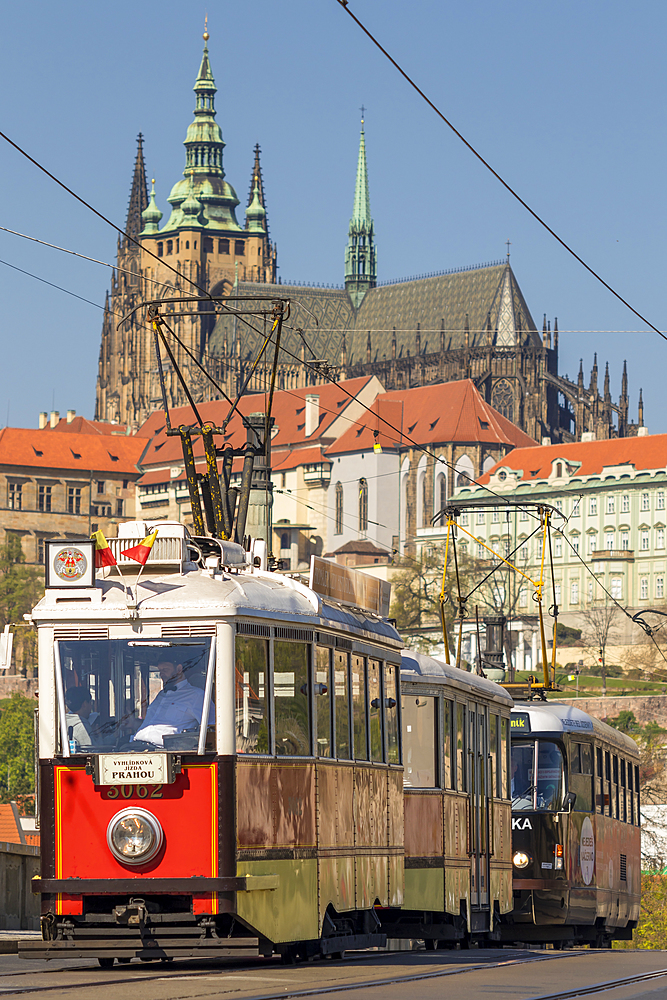 Tourist tram passing a bridge over Vltava River with view to Prague Castle in the background, Prague, Bohemia, Czech Republic, Europe