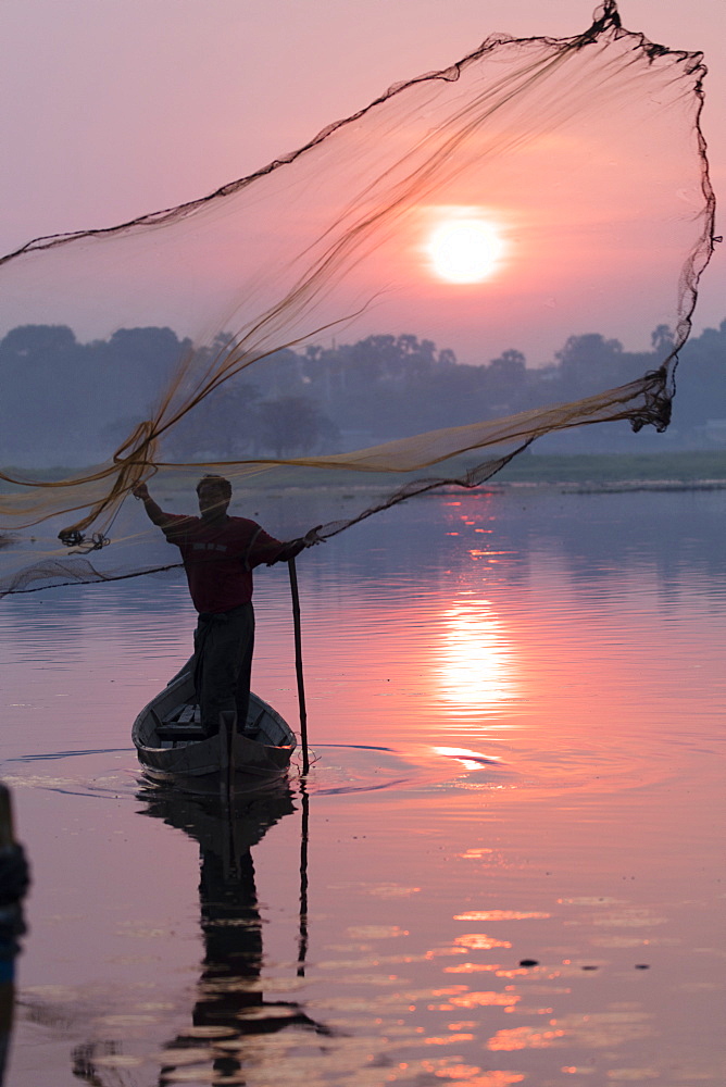 Fisherman casts his net at sunrise on Lake Taungthaman near U Bein Bridge, Myanmar (Burma), Asia