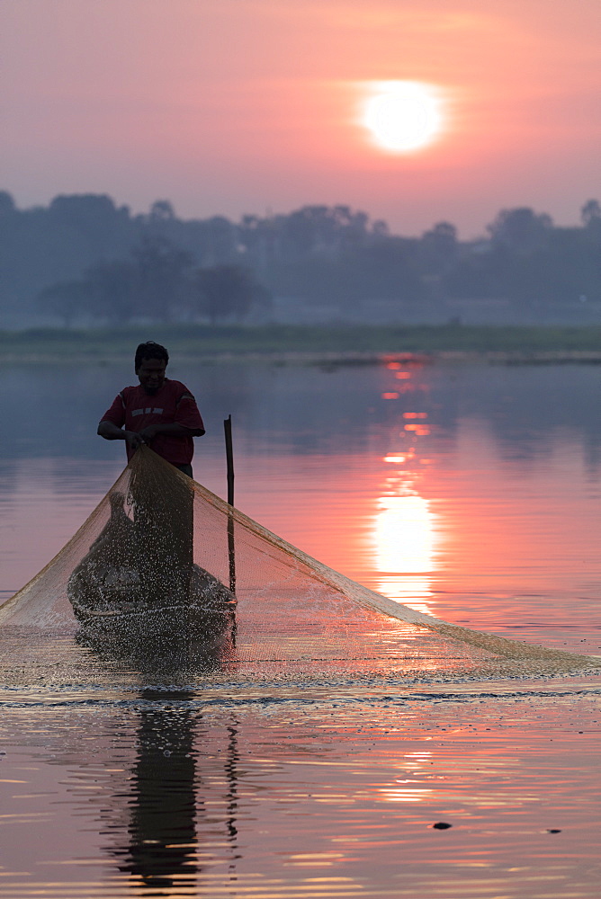 Fisherman casts his net at sunrise on Lake Taungthaman near U Bein Bridge, Myanmar (Burma), Asia