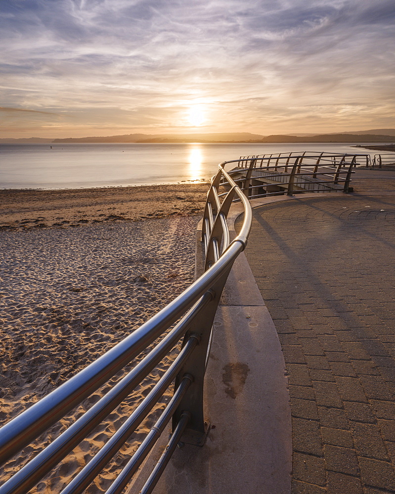 The sun sets in line with railings on the slipway at the RNLI station, Exmouth, Devon, England, United Kingdom, Europe