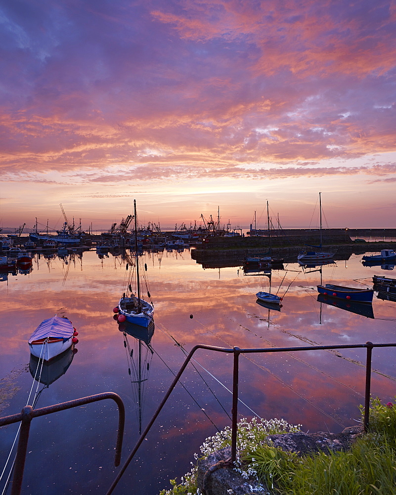 Dawn twilight with underlit clouds, reflections and moored boats in the harbour of the fishing port of Newlyn in Cornwall, England, United Kingdom, Europe